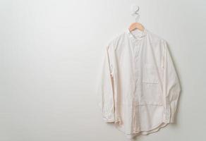 camisa pendurada com cabide de madeira na parede foto