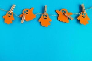 decorações de férias para o halloween. fantasmas de papel laranja pendurados em uma corda em um fundo azul com espaço de cópia. foto