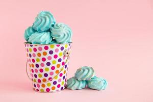 pequeno balde colorido cheio de merengue azul sobre um fundo rosa pastel. conceito mínimo com espaço de cópia. foto