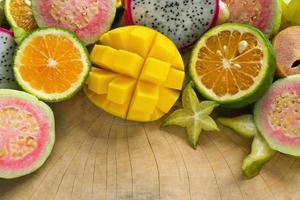frutas tropicais coloridas brilhantes - manga, tangerina, goiaba, fruta do dragão, carambola, sapoti no fundo de madeira. foto