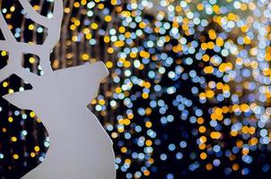 rena de madeira branca decora para o feriado de natal com luzes coloridas de bokeh. foto