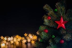 os enfeites de estrela decoram na árvore de natal com fundo de luzes de bokeh estrela. conceito de natal e ano novo. foto