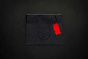 saco de papel de compras preto com preço vermelho em branco sobre fundo preto para o conceito de venda de compras de sexta-feira negra. foto