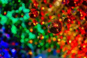 bugiganga dourada pendurada para decorar para o feriado de natal com bokeh colorido de luz e outras bugigangas. foto