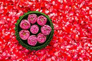 folha de bananeira krathong com flores de lótus para lua cheia da tailândia ou festival loy krathong em fundo de pétalas de rosa vermelha. foto