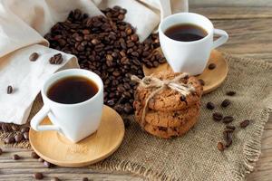 duas xícaras de café expresso fresco na mesa de madeira. grãos de café e biscoitos crocantes na mesa de madeira clara, estilo rústico, caseiro. foto