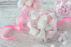 tigela com marshmallows saborosos e fita rosa na mesa branca, closeup foto