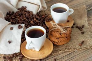 duas xícaras de café expresso fresco na mesa de madeira. grãos de café e biscoitos crocantes na mesa de madeira clara, estilo rústico, caseiro. foto