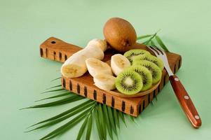 frutas exóticas fatiadas em uma tábua de madeira, close-up. kiwi e banana fatiados para cozinhar smoothie. rico em vitaminas e frutas frescas, alimentos orgânicos saudáveis foto