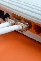 os plugues do cabo de internet estão conectados ao roteador de internet, que fica em um fundo laranja brilhante. itens necessários para conexão com a internet foto