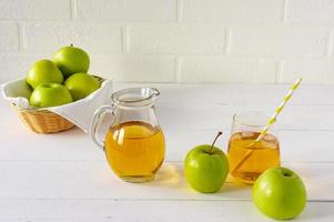suco de maçã caseiro fresco e maçãs verdes na mesa branca. bebida saudável da manhã. foto