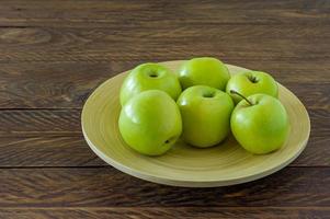 maçãs orgânicas granny smith em um prato na mesa de madeira. foto