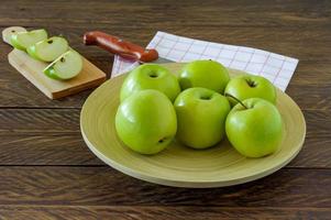 maçãs orgânicas granny smith em um prato na mesa de madeira. foto
