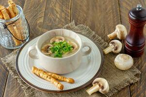 Sopa creme de cogumelos com croutons, ervas e especiarias sobre fundo de madeira foto