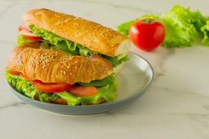 Sanduíche vegano de baguete longa integral com alface, abacate, tomate e queijo. lanche saudável e comida para viagem foto