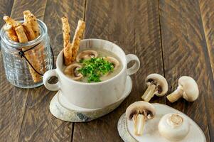 sopa de creme de cogumelos caseiro com cogumelos fatiados e palitos de pão em uma tigela de porcelana foto