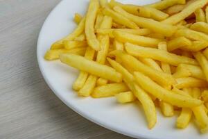 batatas fritas no prato e fundo de madeira foto