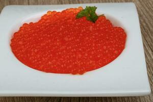 caviar vermelho em uma tigela sobre fundo de madeira foto