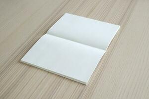 simular livro de papel aberto em branco no fundo da mesa de madeira foto