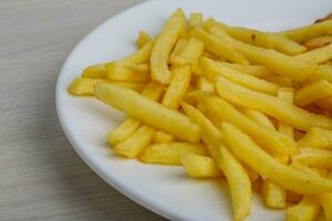 batatas fritas no prato e fundo de madeira foto