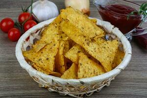 nachos em uma cesta em fundo de madeira foto