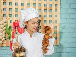 mulher asiática com uniforme de chef está cozinhando na cozinha. foto