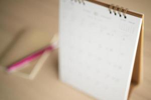 desfoque a página do calendário de perto no fundo da mesa de madeira conceito de reunião de planejamento de negócios foto