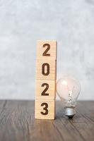 Bloco 2023 com lâmpada. ideia de negócio, criativo, pensando, brainstorm, objetivo, resolução, estratégia, plano, ação, mudança e conceitos de início de ano novo foto