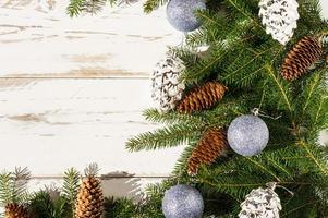 fundo festivo de ano novo com espaço para seu texto. ramos de abeto, floresta e cones de prata, bolas azuis brilhantes. fundo de madeira branco. foto
