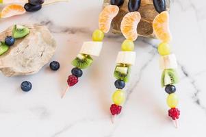 frutas frescas em espetos, composição em pedras. sobremesa de verão. foto