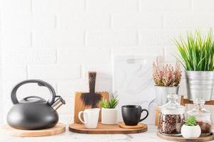 fundo de cozinha branca elegante com utensílios de cozinha e plantas de casa verdes em belos vasos. vista frontal. o conceito de casas limpas. foto