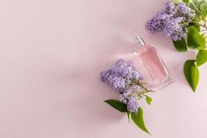 frasco de perfume de vista superior com perfume ou água de toalete no contexto de ramos lilás. uma cópia do espaço. o conceito de fragrâncias naturais. foto