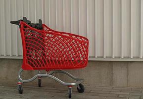 compras vermelhas vazias no fundo da parede industrial. carrinho de compras no supermercado. venda, desconto, vício em compras, sexta-feira negra, conceito de economia. tendência da sociedade de consumo. conceito de compras on-line. foto