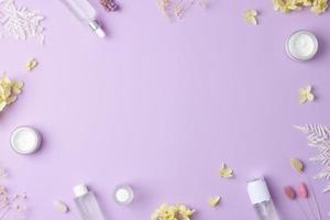 produtos cosméticos para cuidados com a pele com flores em fundo rosa. postura plana, copie o espaço foto