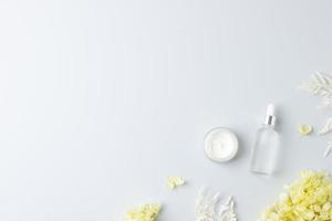 produtos cosméticos para cuidados com a pele com flores em fundo cinza. postura plana, copie o espaço foto