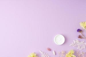 pote de creme cosmético com flores no fundo rosa. postura plana, copie o espaço foto