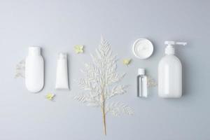 composição cosmética com produtos cosméticos para a pele e flores em fundo cinza. postura plana, copie o espaço foto