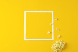 fundo cosmético com flores e moldura branca em amarelo. postura plana, copie o espaço foto