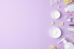 produtos cosméticos para cuidados com a pele com flores em fundo rosa. postura plana, copie o espaço foto