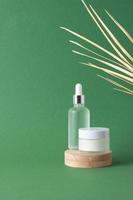 produtos cosméticos para cuidados com a pele com pódio de madeira e folha de palmeira sobre fundo verde. close-up, copie o espaço foto