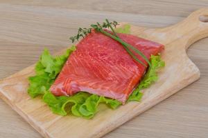 salmão na tábua de madeira e fundo branco foto