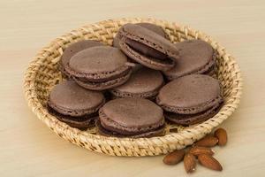 macaroons de chocolate em uma cesta em fundo de madeira foto