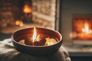 aconchegante inverno ou noite de outono em casa. café quente com colher metálica dourada, cobertor quente, guirlanda e luzes de velas, conceito de hygge sueco. foto