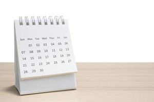 calendário de mesa branco no tampo da mesa de madeira isolado no fundo branco foto