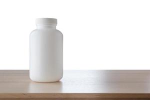 frasco de remédio na mesa de madeira isolada no fundo branco foto