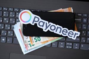 ternopil, ucrânia - 6 de setembro de 2022, o logotipo de papel payoneer está no laptop preto com notas de euro. payoneer é uma empresa americana de serviços financeiros que fornece transferência de dinheiro online foto