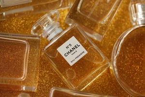 ternopil, ucrânia - 2 de setembro de 2022 chanel número 5 eau estréia mundialmente famoso frasco de perfume francês entre outros perfumes em fundo de brilho brilhante em cores amarelas foto