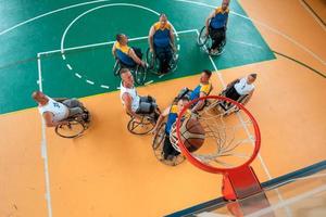 guerra com deficiência ou veteranos de trabalho mistos de raça e idade equipes de basquete em cadeiras de rodas jogando uma partida de treinamento em um ginásio de esportes. conceito de reabilitação e inclusão de pessoas com deficiência. foto