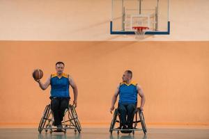 Veteranos de guerra com deficiência equipes de basquete de raça mista e idade em cadeiras de rodas jogando uma partida de treinamento em um ginásio de esportes. conceito de reabilitação e inclusão de pessoas com deficiência foto