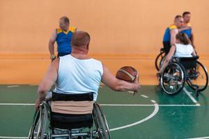 Veteranos de guerra com deficiência equipes de basquete de raça mista e idade em cadeiras de rodas jogando uma partida de treinamento em um ginásio de esportes. conceito de reabilitação e inclusão de pessoas com deficiência foto